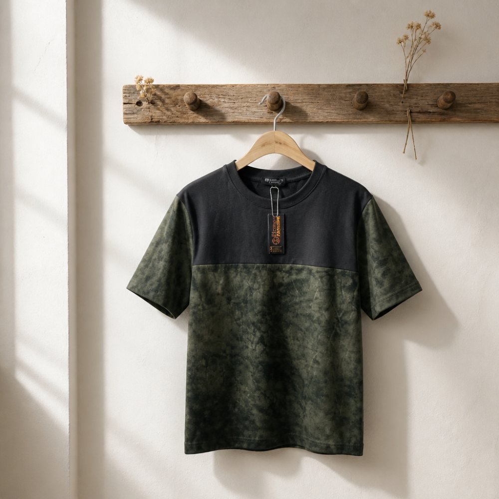 A modern two-tone T-shirt combining a clean black upper panel with a rich, textured olive-green finish. The relaxed fit and subtle color contrast give it a minimal, rugged streetwear aesthet